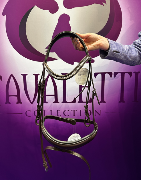 Cavaletti Collection bridle with a crystal browband held in front of a purple branded backdrop.
