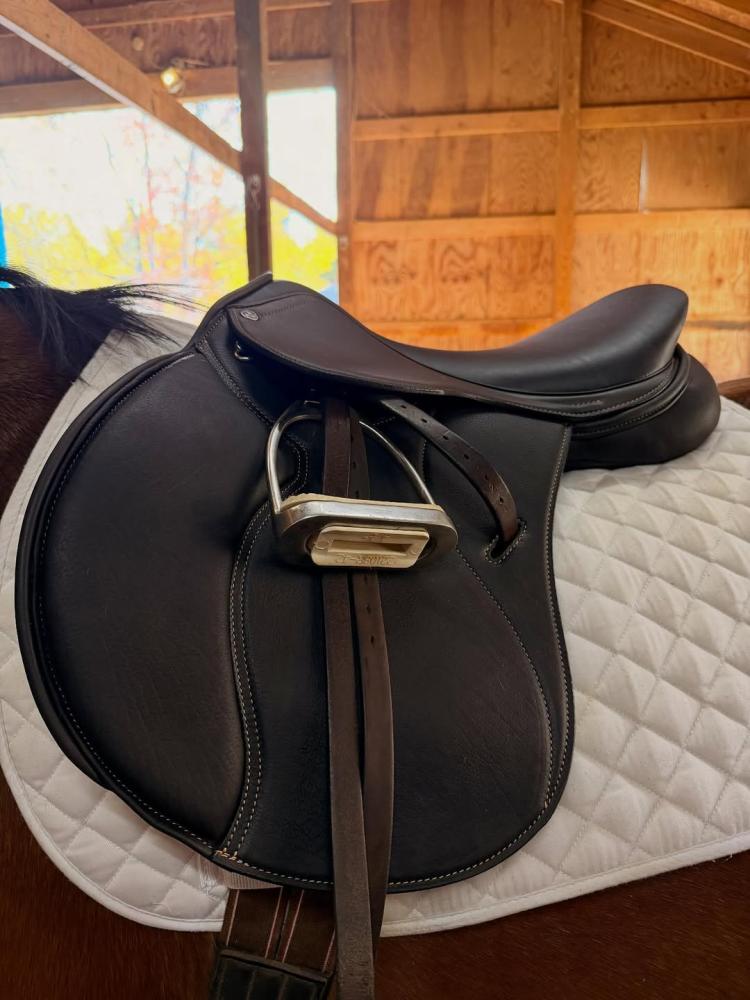 Cavaletti Collection brown saddle on a horse with a white quilted pad inside a warm stable setting.