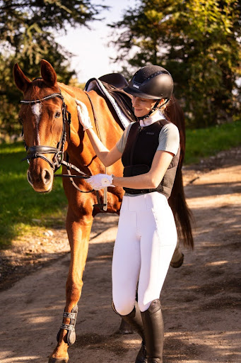 Handler walking a brown horse along a quiet outdoor path, both in Cavaletti Collection tack. Photo credit from vcresch.
