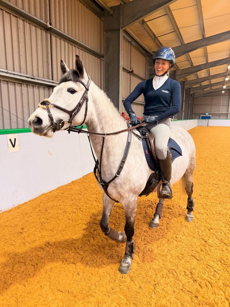 Rider on a gray horse working inside an indoor arena, both in Cavaletti Collection tack. Photo credit: scottisheventer.