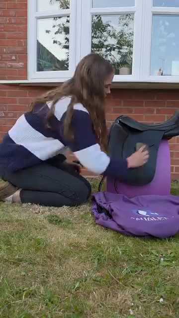 Team Allerton rider schooling a horse in an outdoor arena using Cavaletti tack, viewed from behind during flatwork training.