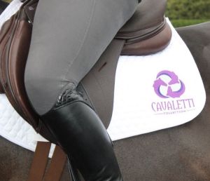 Equestrian riding with brown Cavaletti Collection ASX Atherstone Girth and white branded saddle pad on horse.